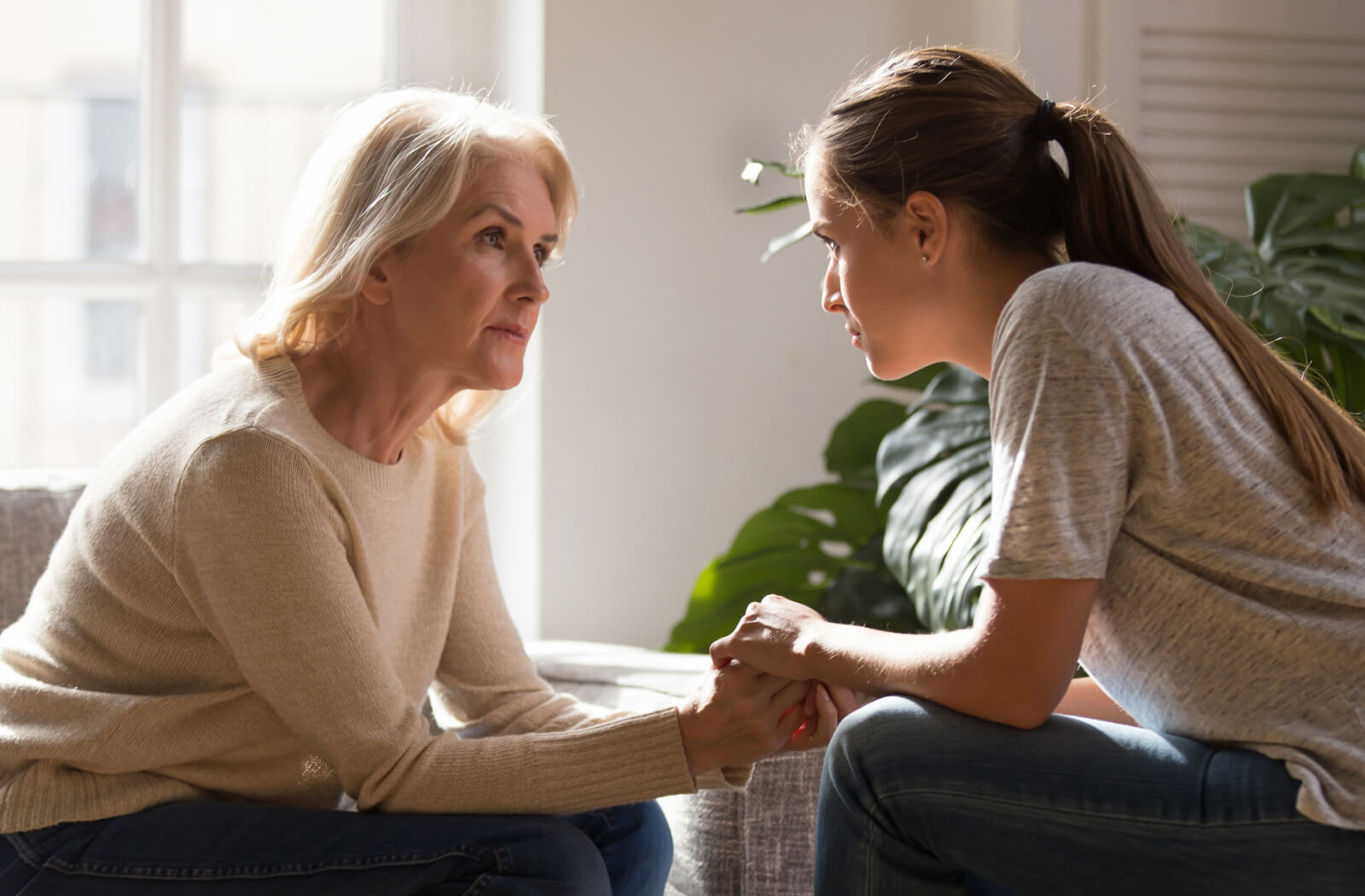 A senior with dementia sitting across from their grandchild, holding hands and making eye contact during a conversation.