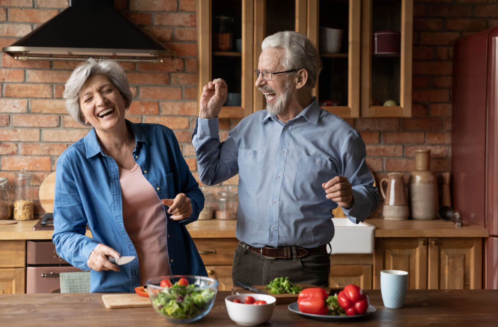 A senior couple being silly and having fun while preparing a new recipe in their kitchen.