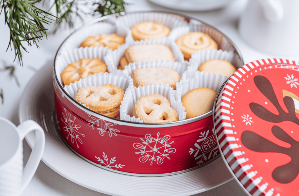 A red tin of christmas sugar cookies sits on a table.